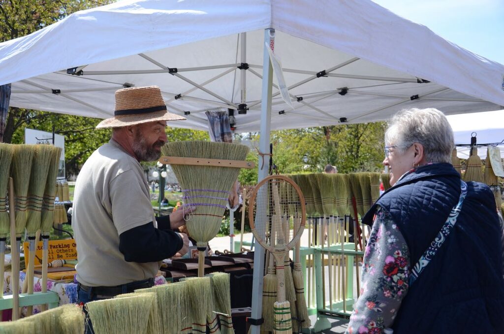 Broom maker showing his art to a customer at the Lewisburg Arts Festival