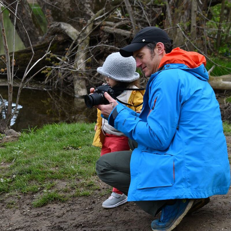 Photographer and child next to a creek on a nature photo hike