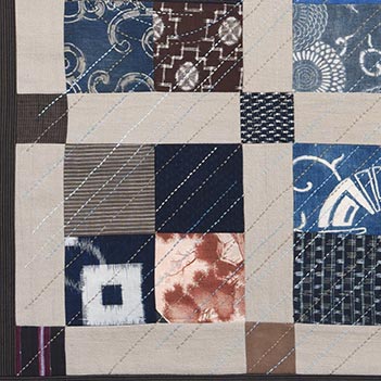 The sashiko inspired stitching on this taupe and blue patchwork wall hanging inspired its name 22Wind Rain22 detail